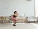 Woman in activewear doing squats at home, promoting a healthy lifestyle and fitness routine.
