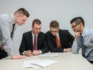 four men looking to the paper on table