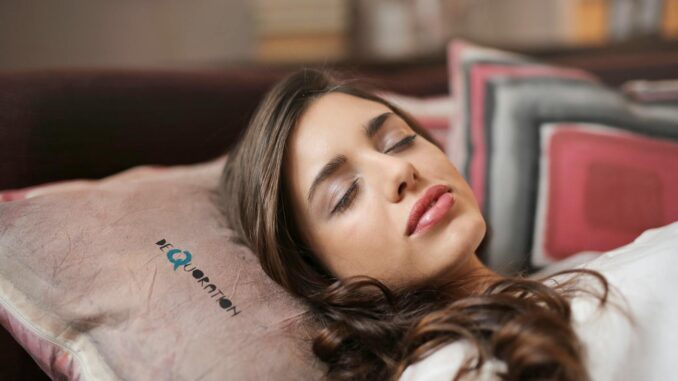 A woman peacefully sleeping indoors on a pillow, exuding comfort and relaxation.